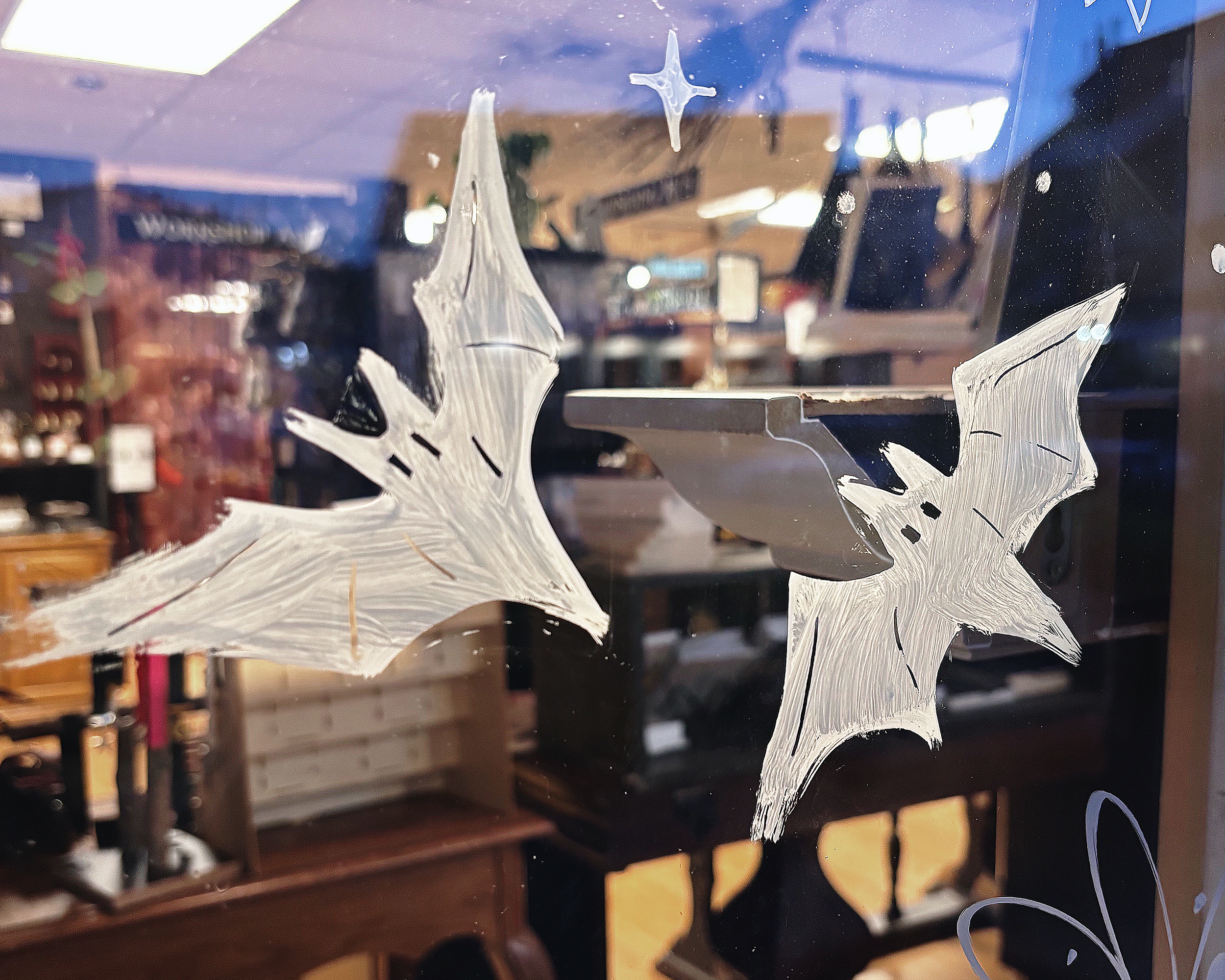 Hand-painted bats on glass window in white paint.