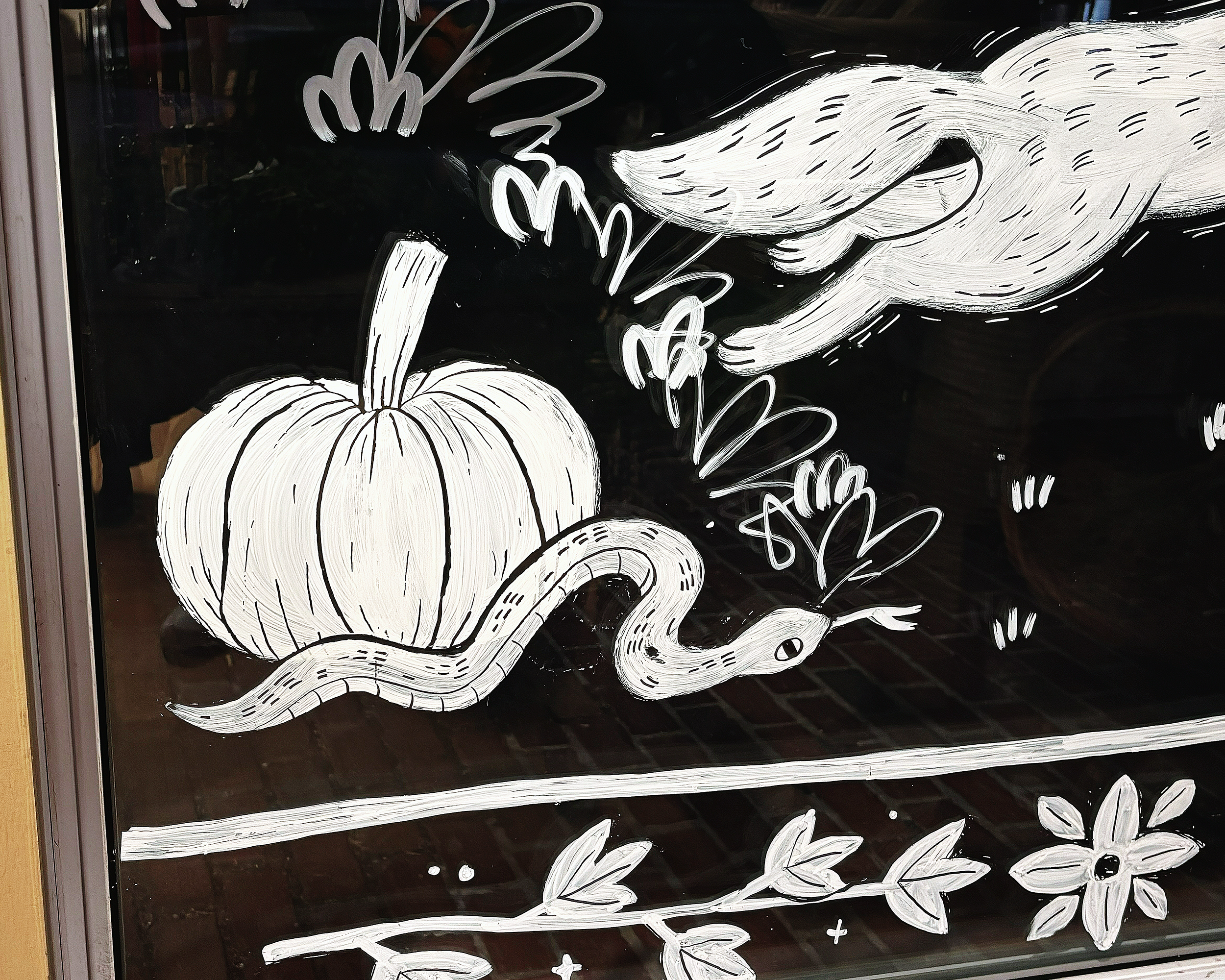 Hand-painted snake and pumpkin on glass window.