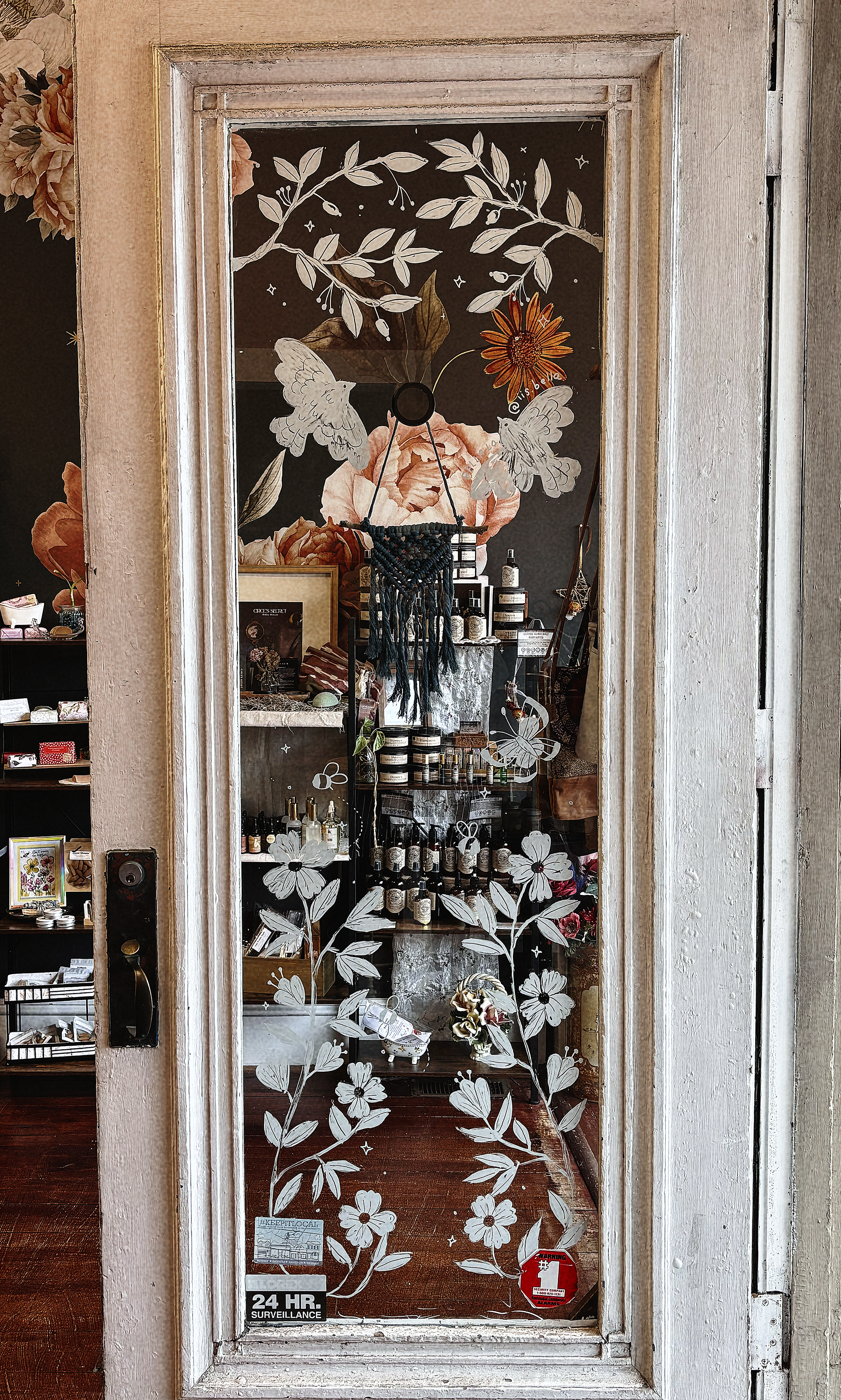 Glass door with hand-painted white floral, leaf, and bird designs.