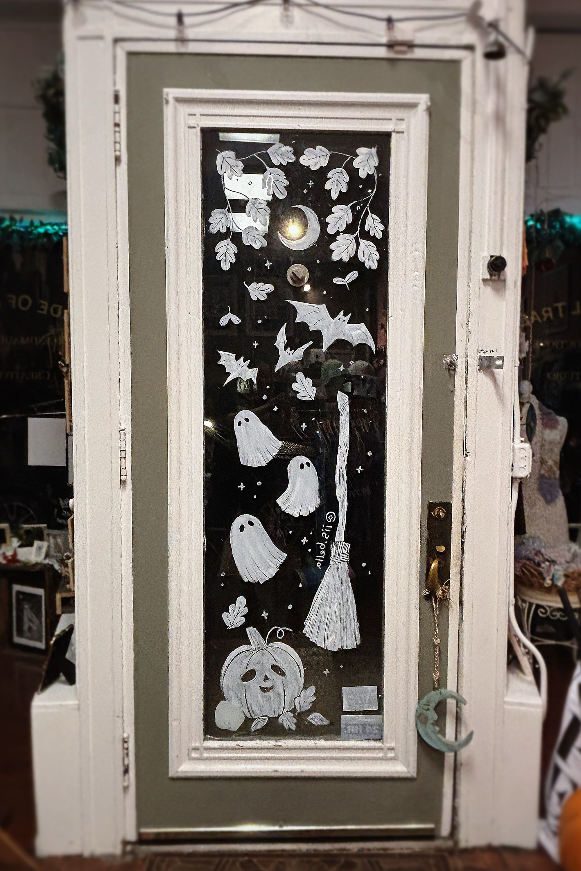 A hand-painted mural of ghosts, bats, a moon, leaves, and a pumpkin on a glass door.