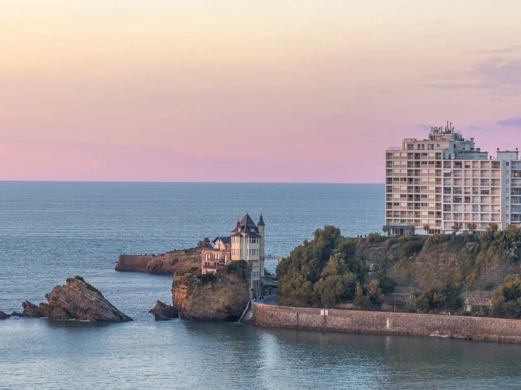 Sunset Biarritz beach in warm autumn light with waves and cliffs in the background