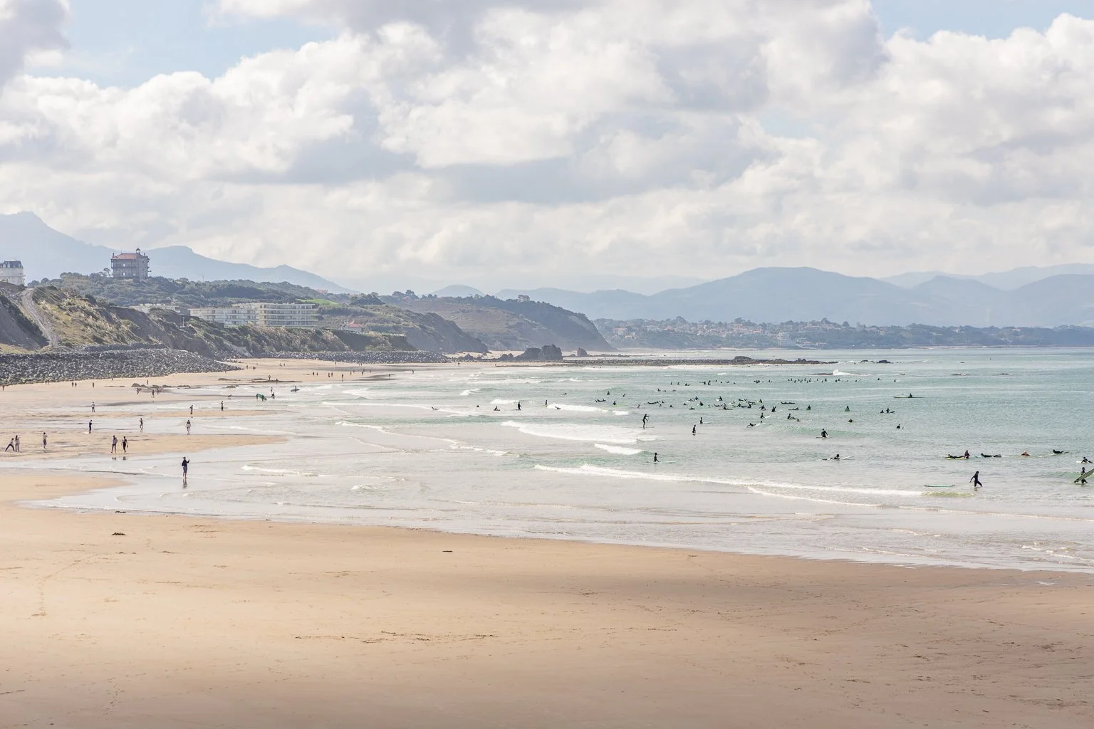 Sunrise view of Biarritz Grand Plage with elegant Belle Époque buildings and surfers in the waves