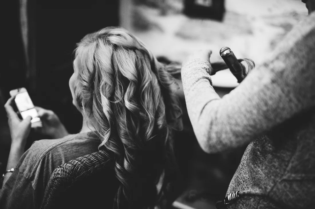 Bridesmaid having her hair curled at the bridal preps. Black and white photography