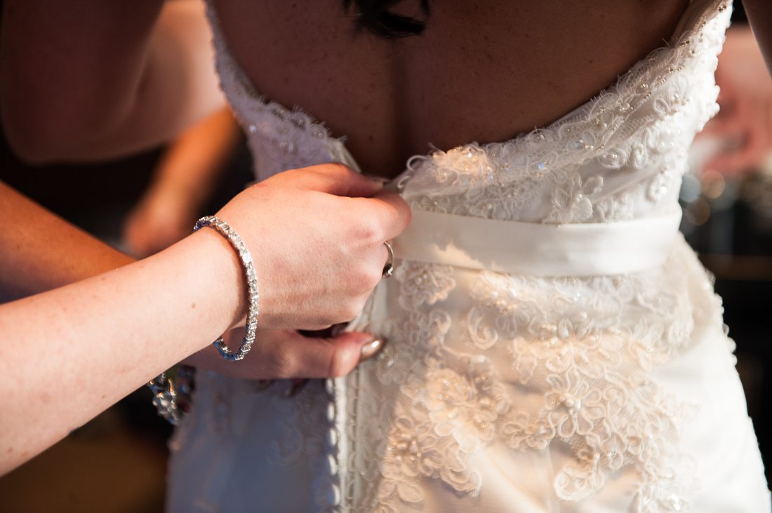 Close up of brides dress being fastened 