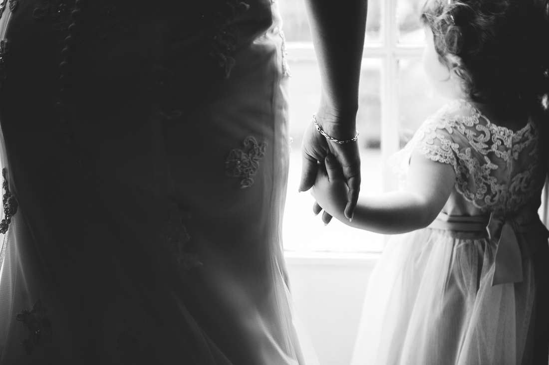 close up shot of bride and daughter holding hands. black and white wedding photography