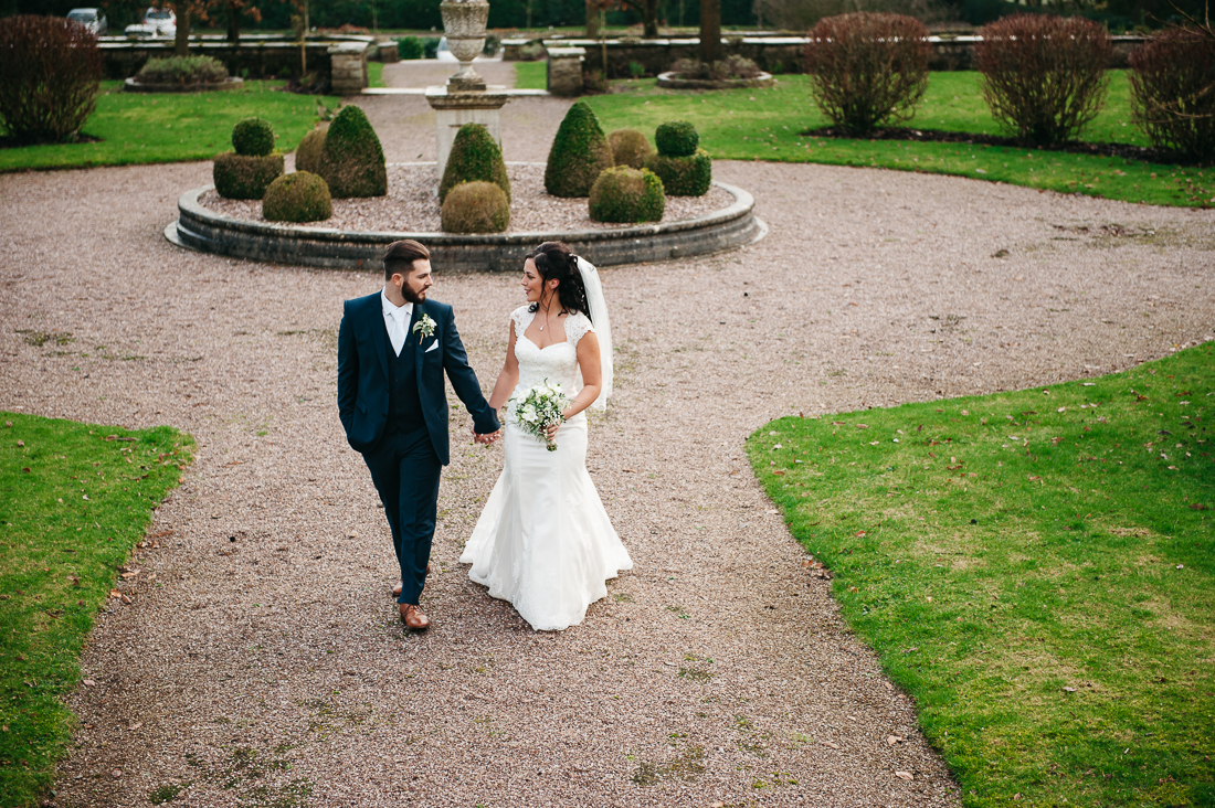 Bride and groom walking together through the grounds of Eaves Hall. Documentary wedding photography