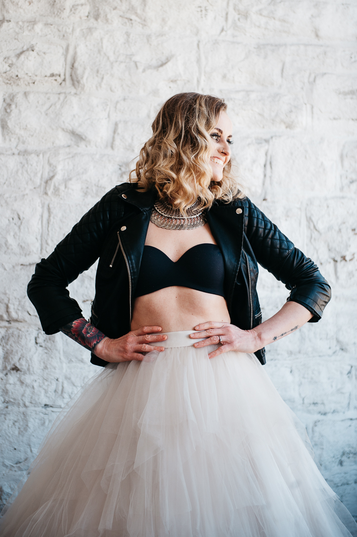Alternative bride wearing leather jacket and crop top with a tulle skirt at her industrial style warehouse wedding.