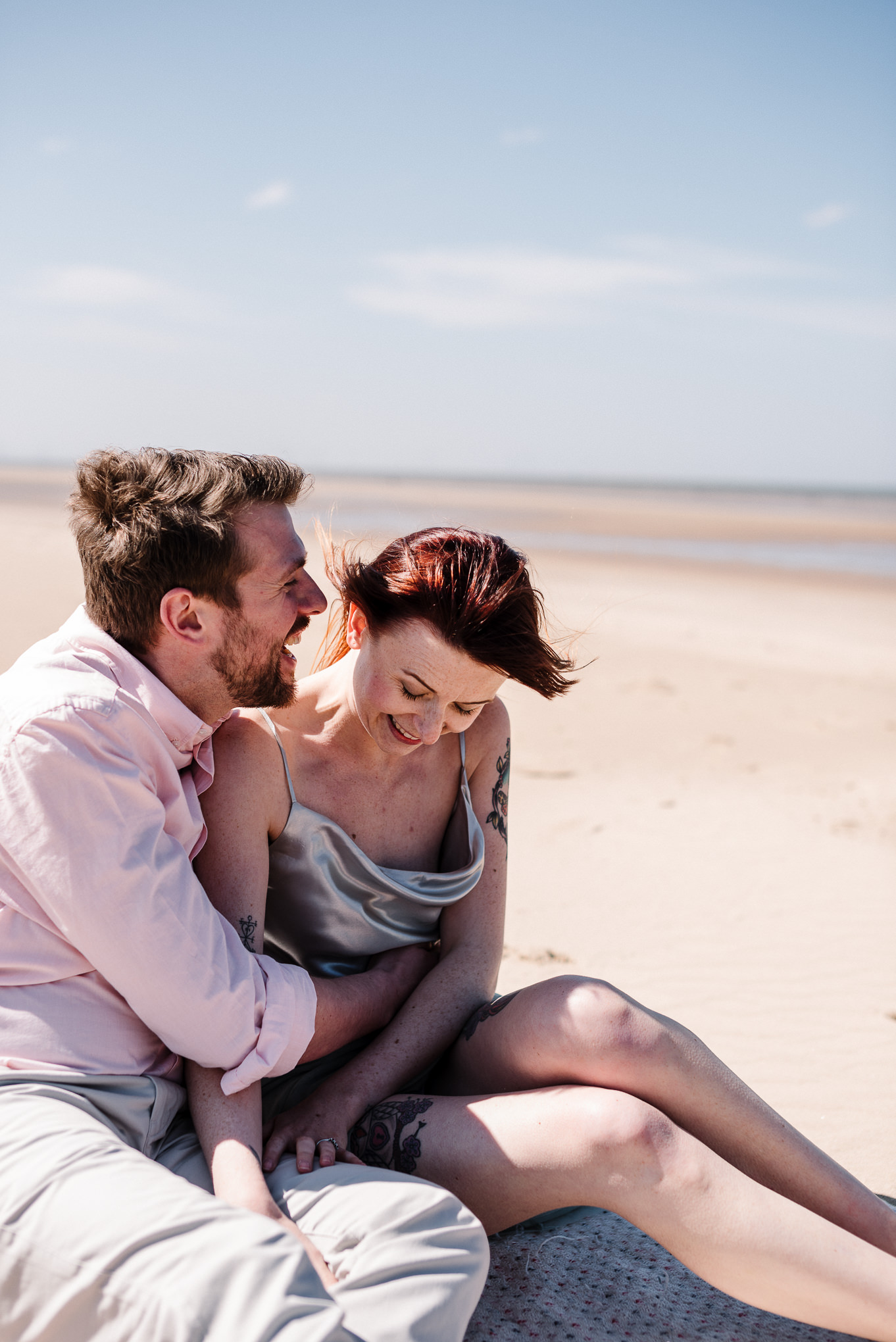 Bride and groom sat together on the sands at Formby Beach, Liverpool.