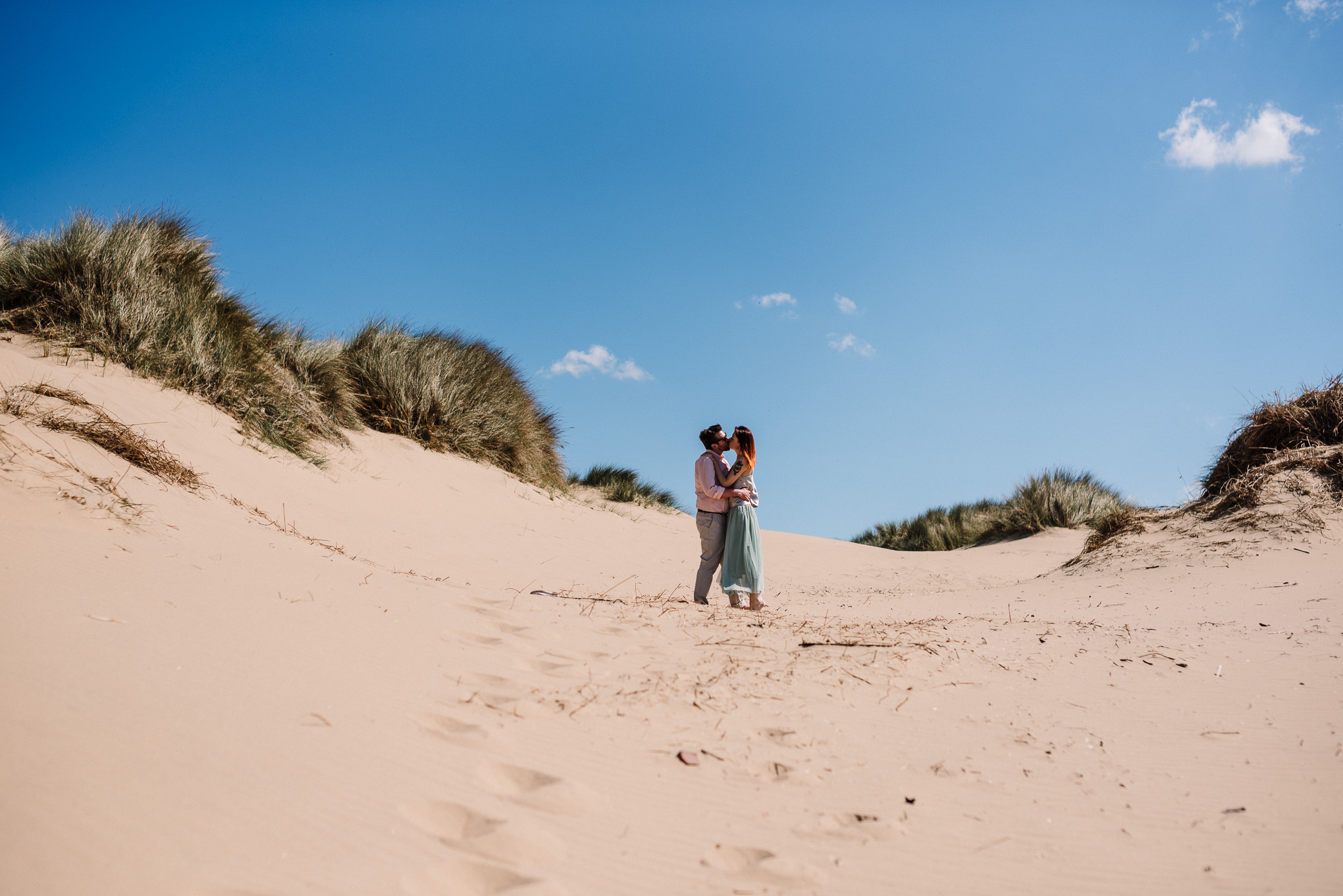 Landscape shot of sand dunes and bride and groom on the beach. Liverpool wedding photography