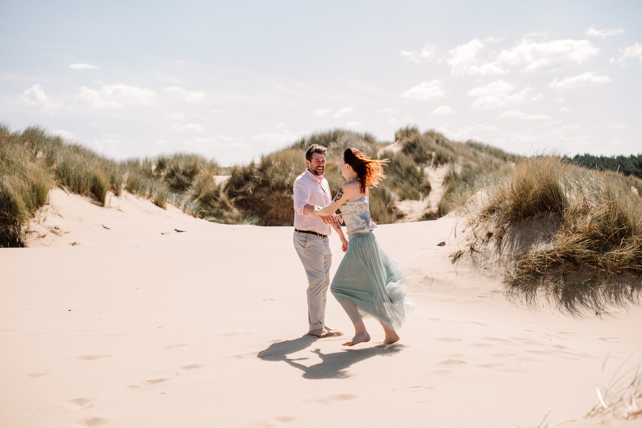 Natural shot of bride and groom dancing on the sand dunes. Beach wedding photography, Liverpool