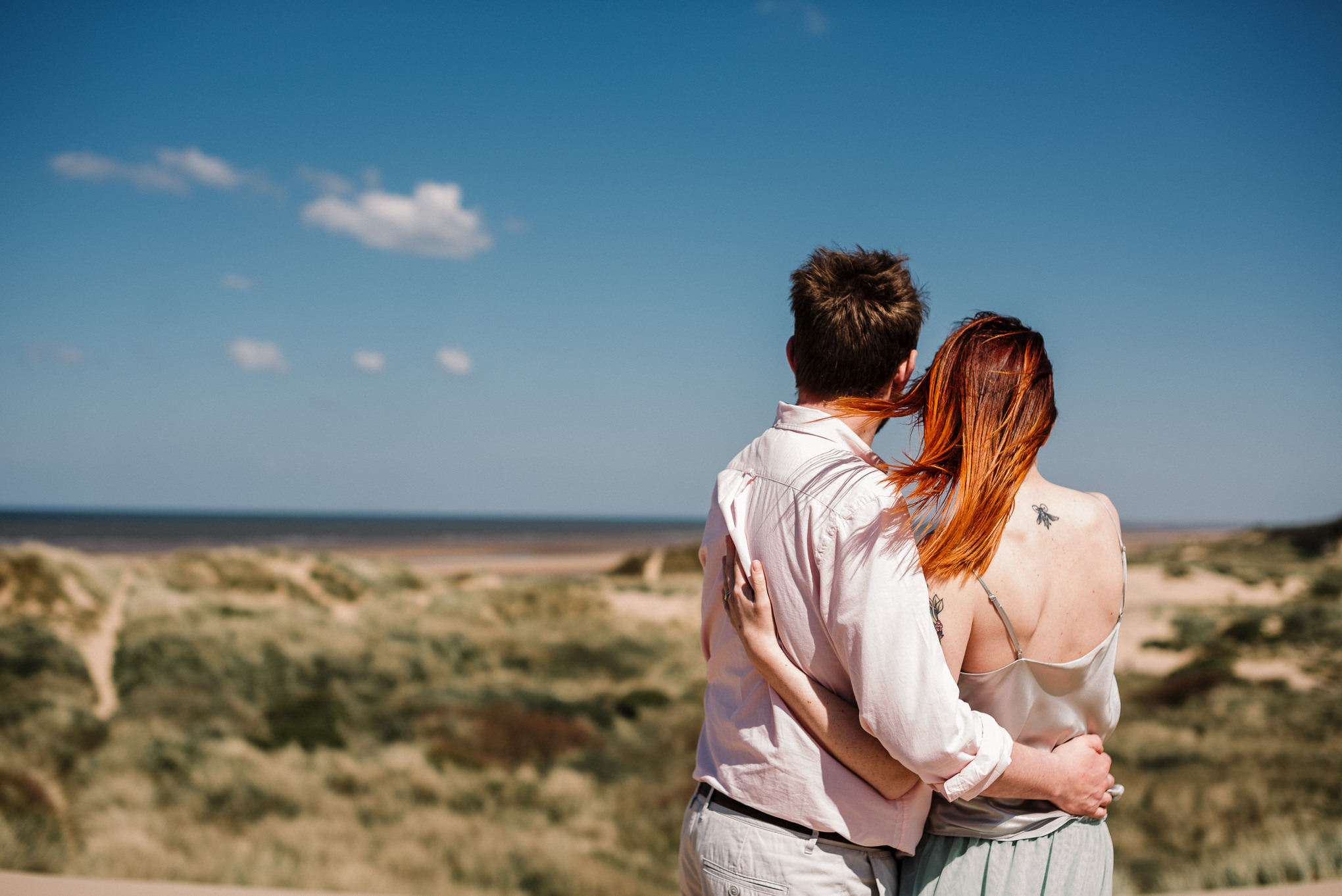 Bride and groom looking out to sea from the sand dunes on Formby beach. Liverpool wedding photography