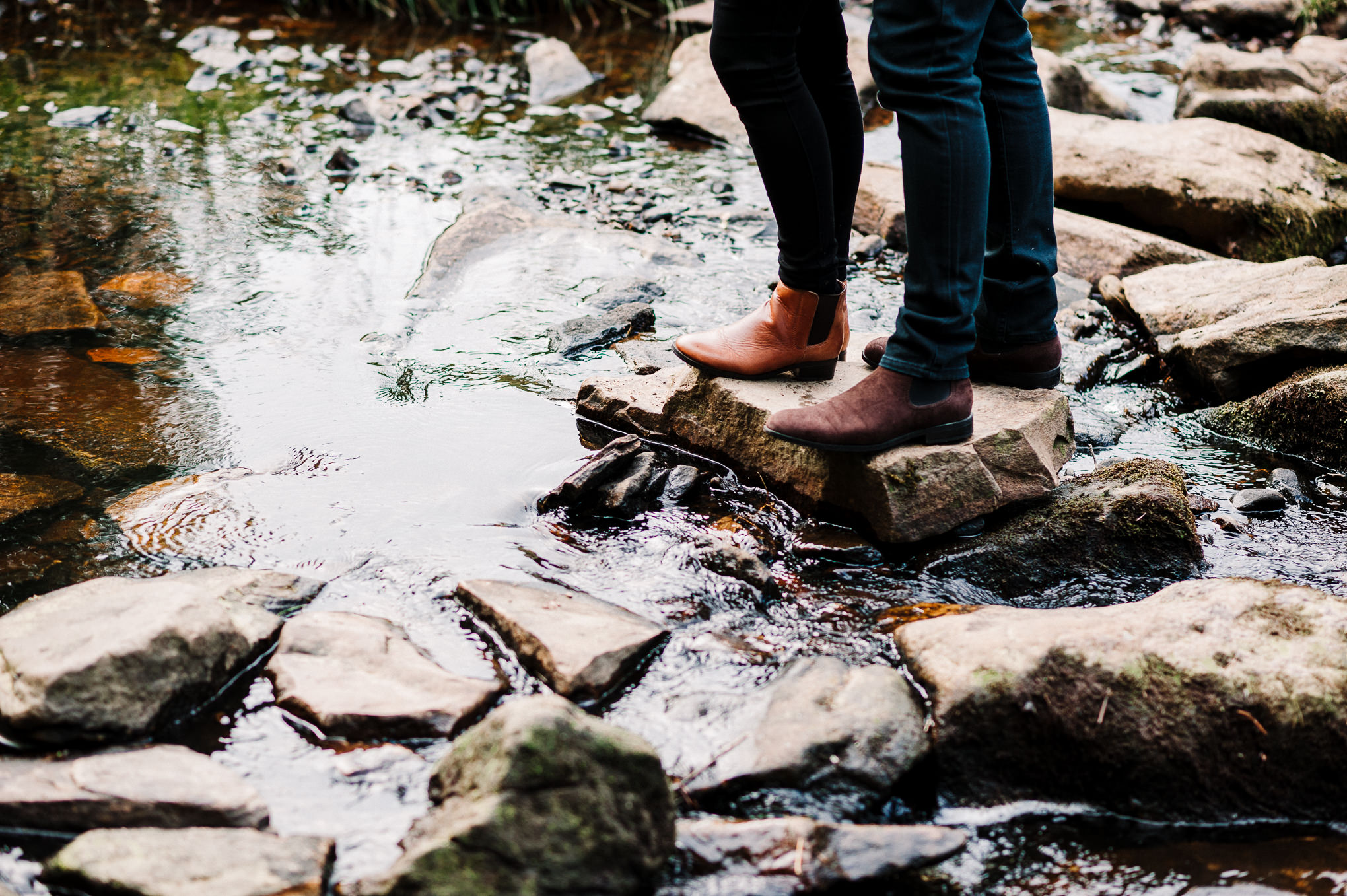 Close up shot of couple stood on stones in the river at Entwistle Reservoir in Bolton, Lancashire.