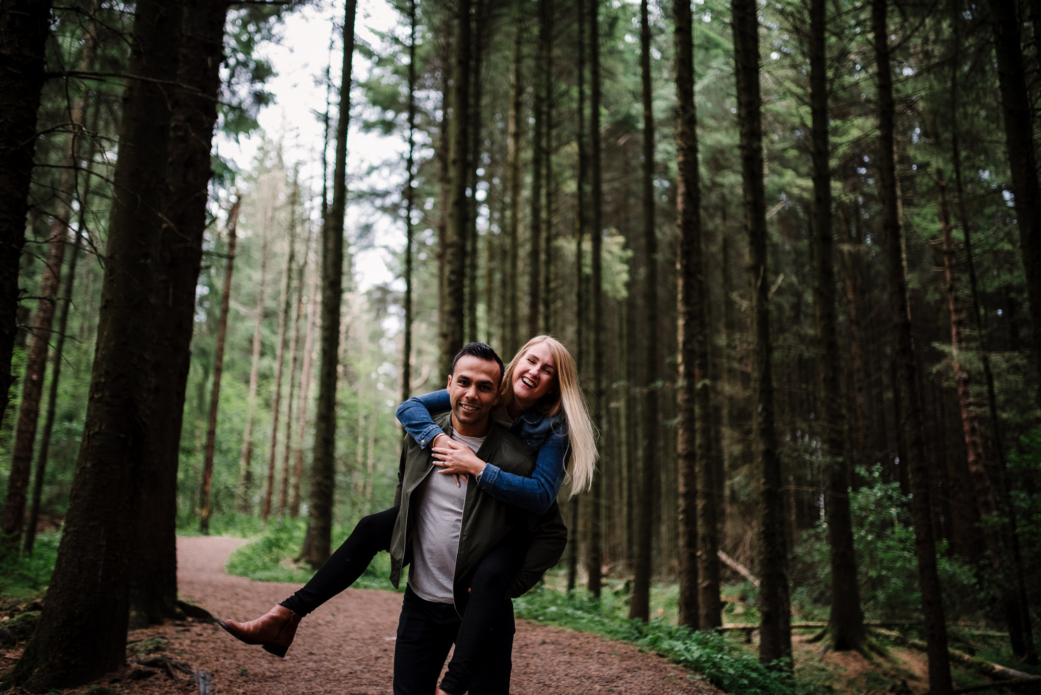 Natural photo of couple running together in the woods at Entwistle Reservoir in Bolton, Lancashire. 