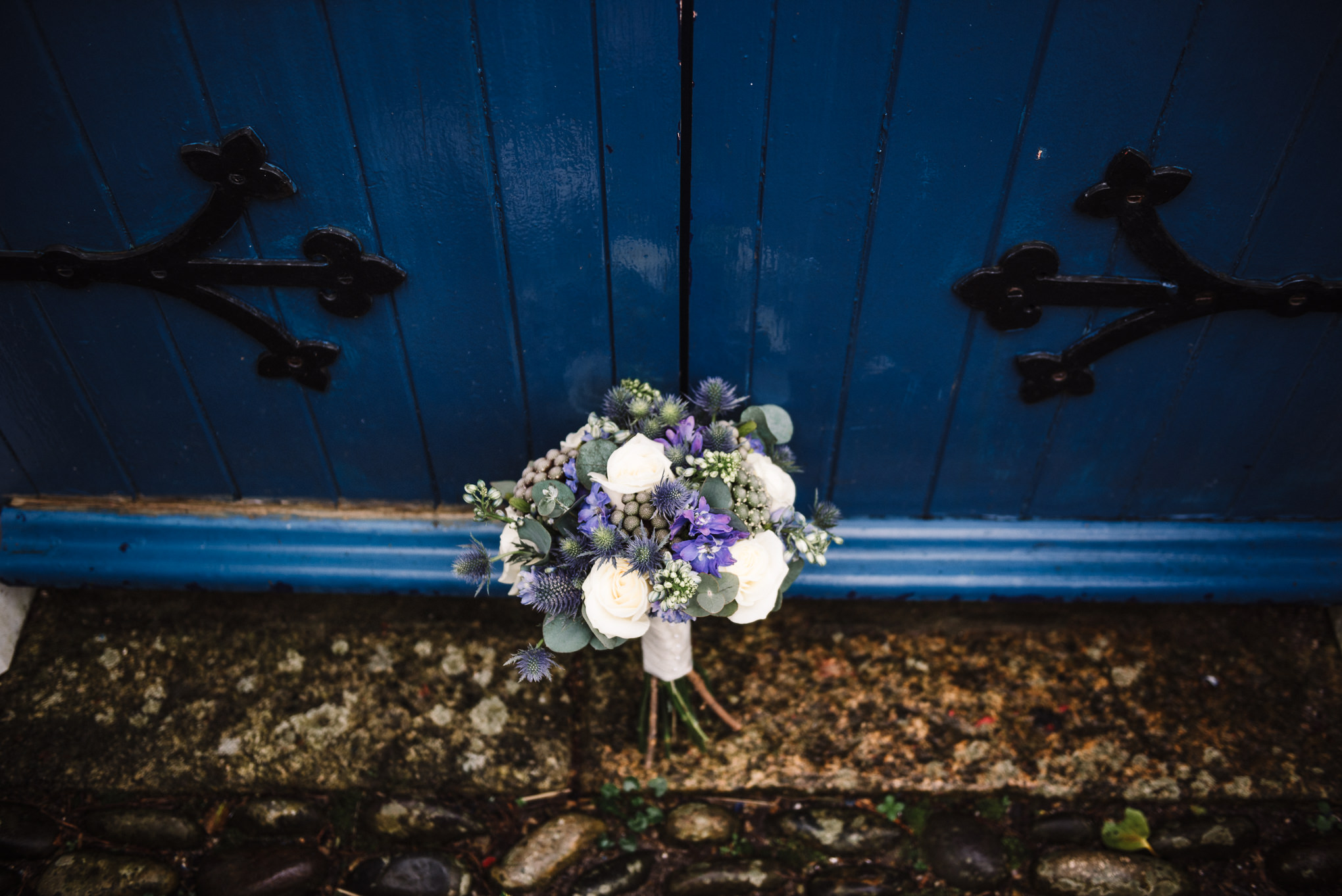 Wedding flowers up against blue door of the wedding venue