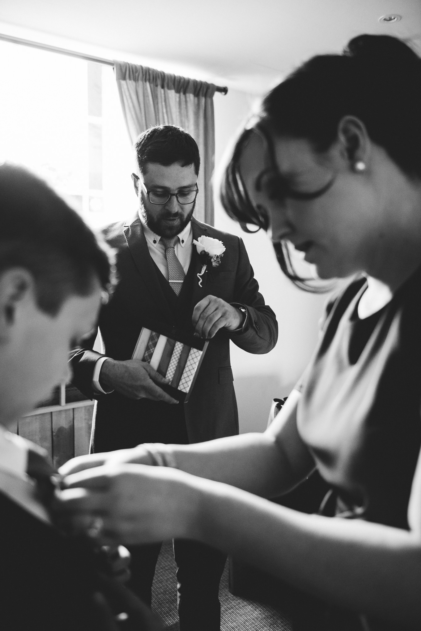 Natural shot of the Groom opening his wedding gift from bride.