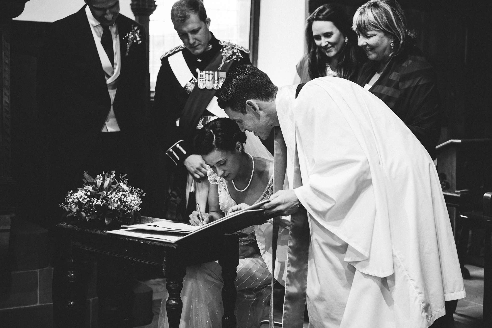 black and white documentary shot of the bride signing the register 