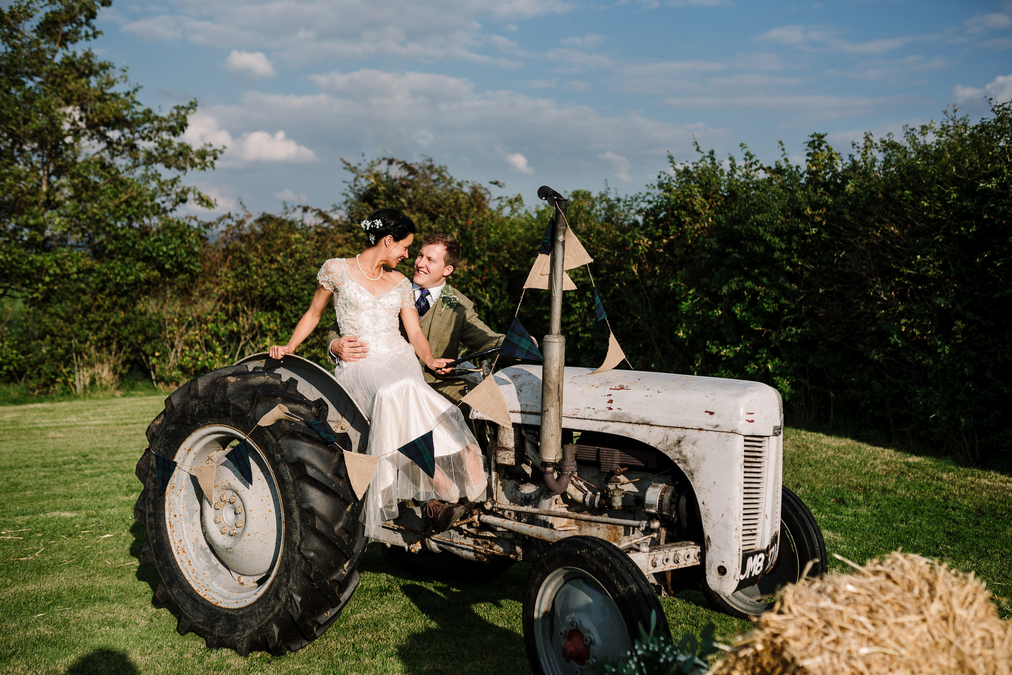 Portrait of bride and groom on the farms tractor. Lake District wedding photographer