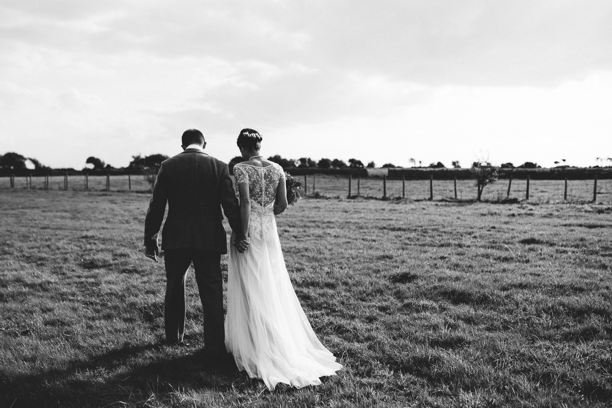 Natural black and white photo of bride and groom walking on the farm.