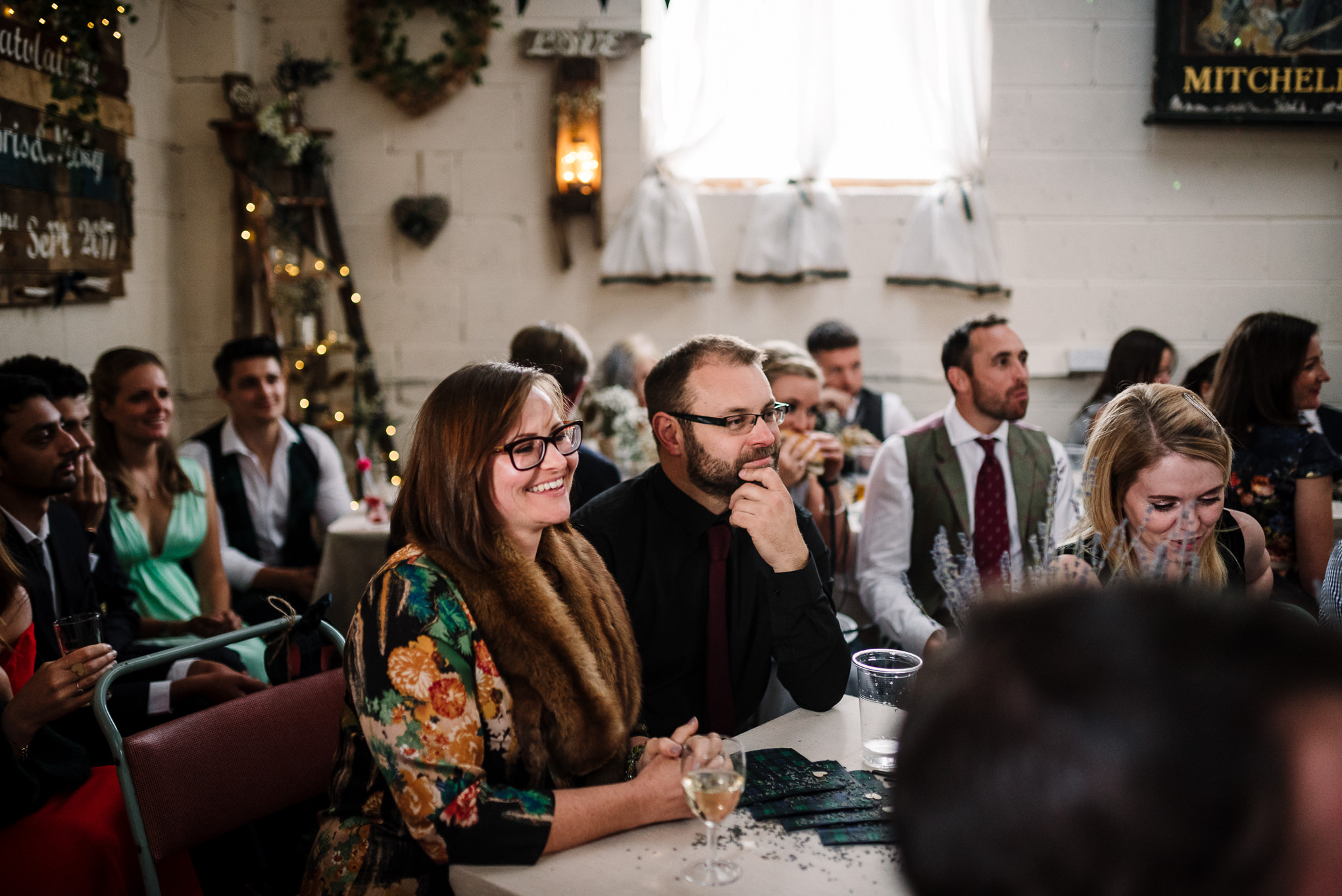 Guests laughing during speeches. Natural wedding photography in the Lake District.