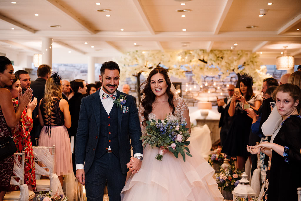 Natural photo of bride and groom walking down the isle together.