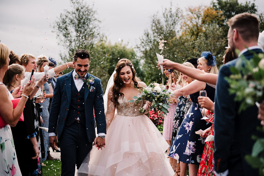 Bride and groom walking through a isle of confetti. Natural wedding photography