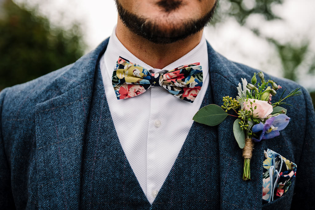 Detailed shot of floral bow tie and button hole on vintage style suit. Modern wedding photography