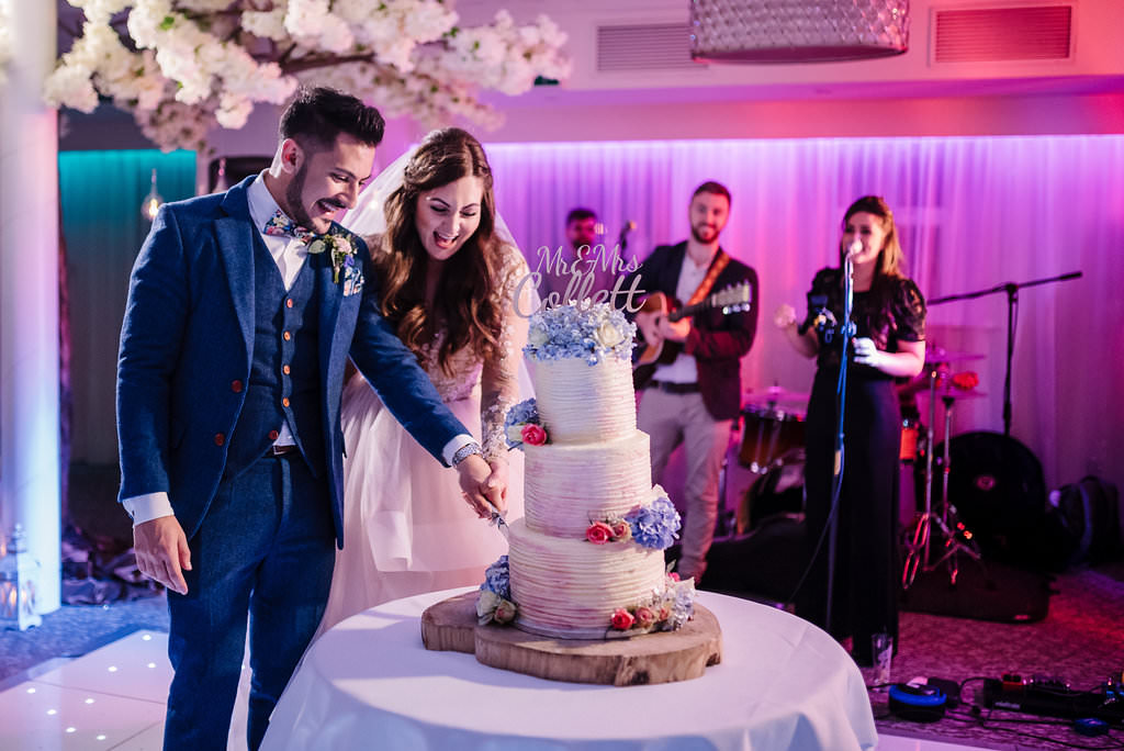 colourful portrait of the bride and groom cutting their wedding cake. Lancashire wedding photography