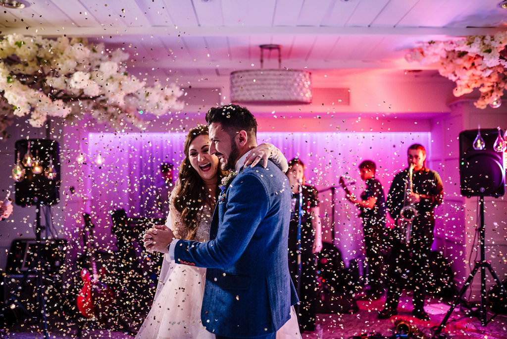 Relaxed shot of bride and groom dancing with confetti in the air. Lancashire wedding photography