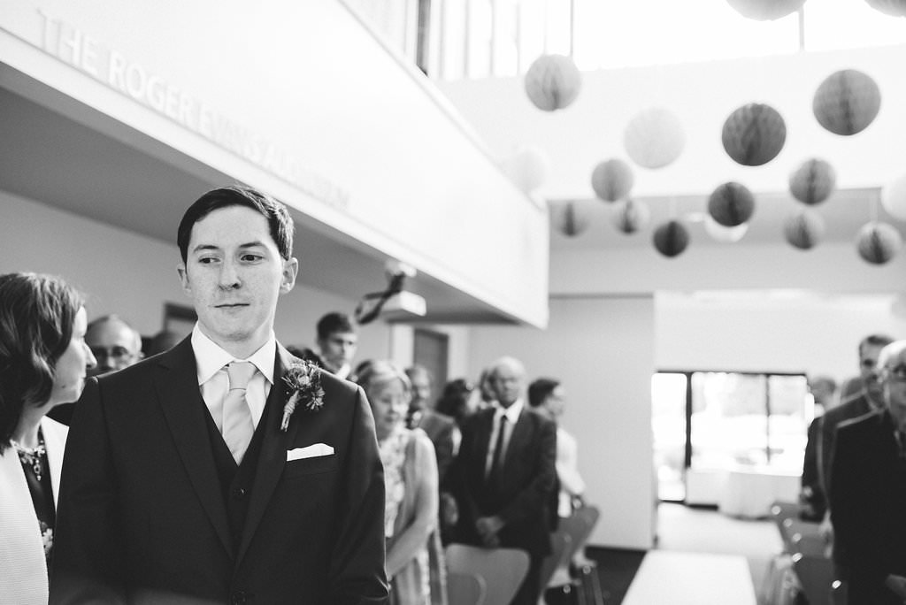 Black and white photo of groom waiting for his bride