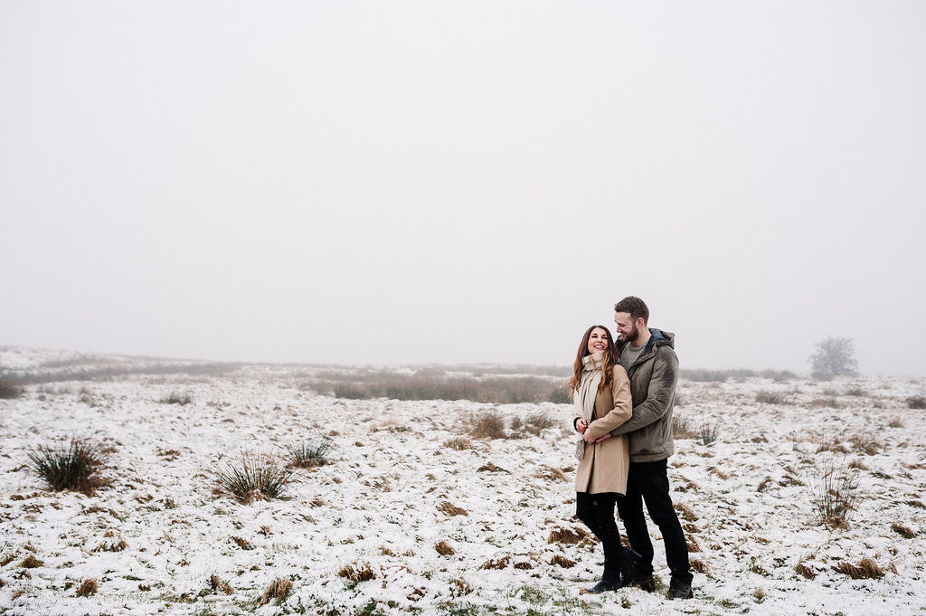 Natural shot of couple hugging with snow landscape. Lancashire engagement photography