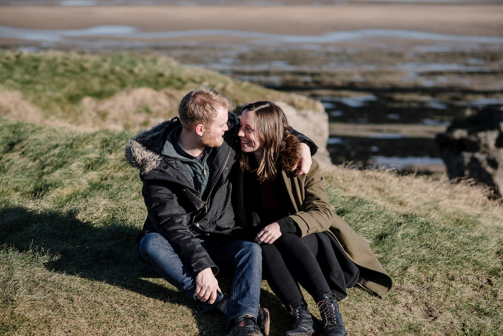 Natural photo of couple sat on the hillside at Hilbre Island. 