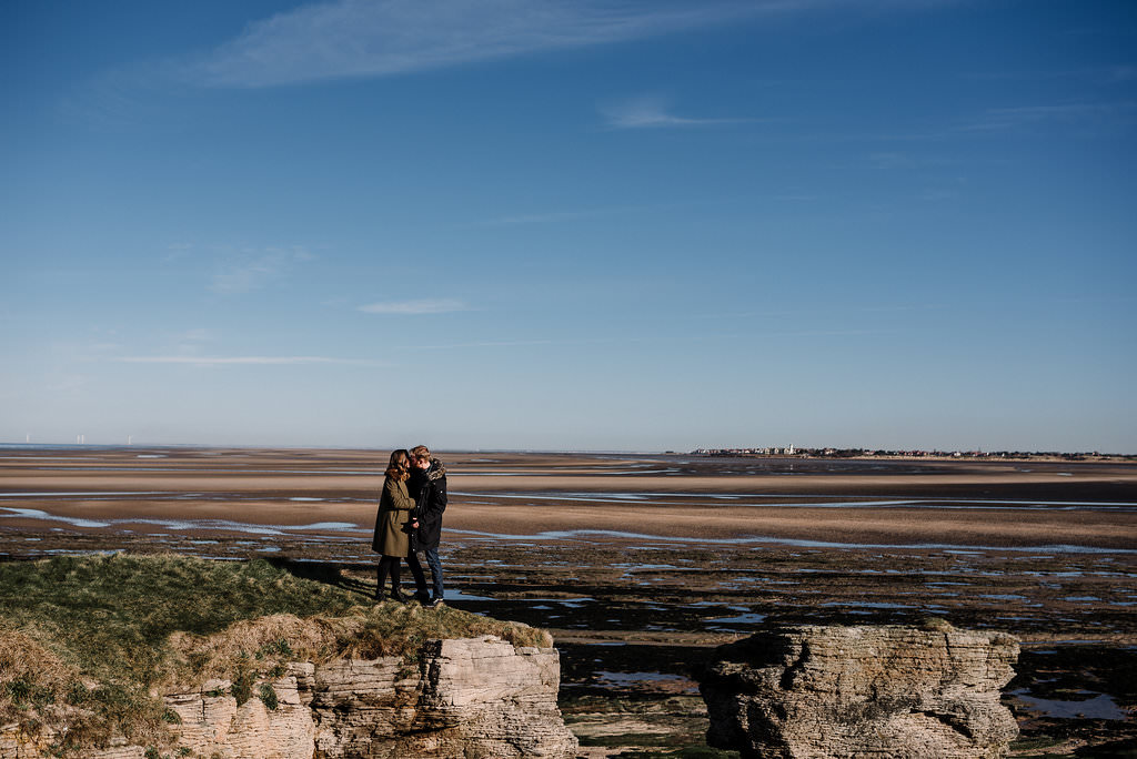 Landscape photo of inland views from Hilbre Island with couple kissing 