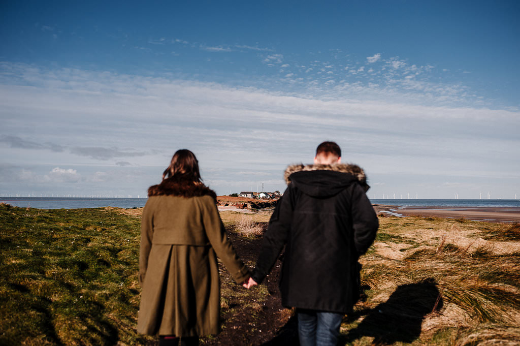 Natural photo of couple walking towards the Island in West Kirby