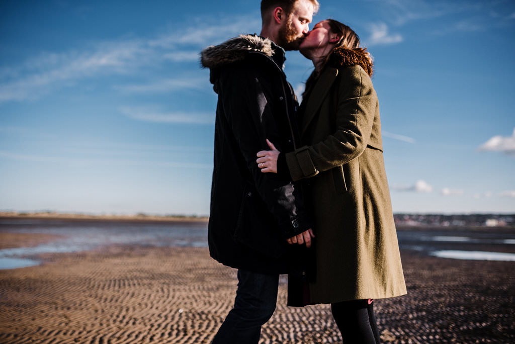 Bright and colourful portrait of couple kissing on the beach in West Kirby. Engagement Photography Merseyside.