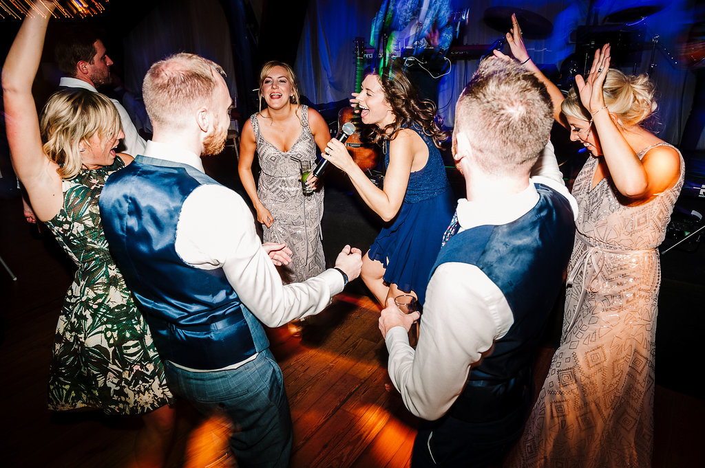 Colourful dance floor shot of guest dancing at Rivington Hall Barn wedding.