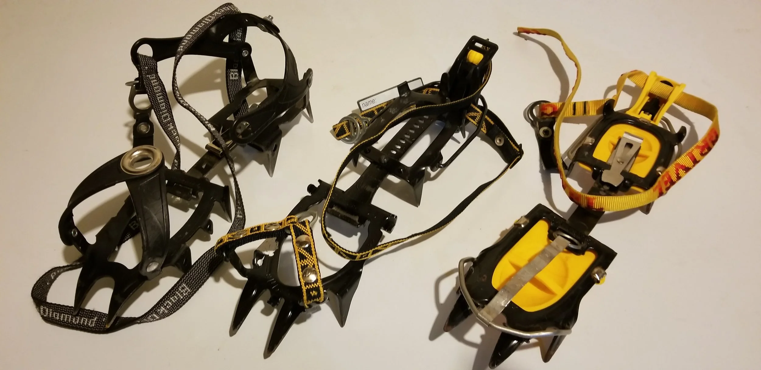 Three sets of my crampons. Left to right, Black Diamond strap-on type, Charlet hybrid type with strap at toe and bail at heel, Grivel with bails on toe and heel.