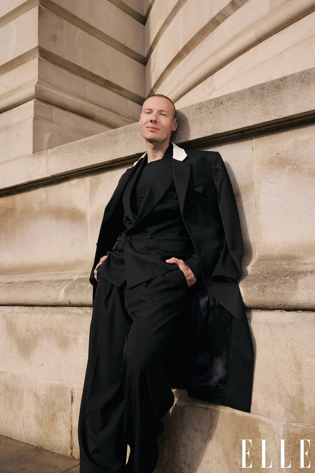 Personal branding street style fashion photography of fashion consultant Bernard Garby leaning against historical stone building for ELLE magazine print issue.