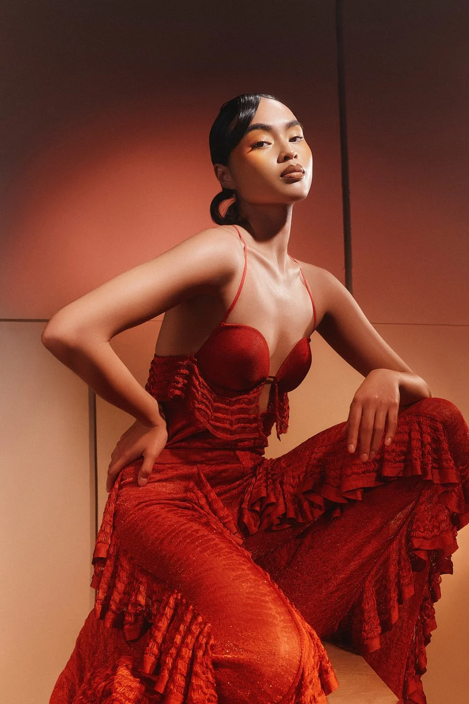 Fashion photography in London of model wearing red lit up by red light in studio