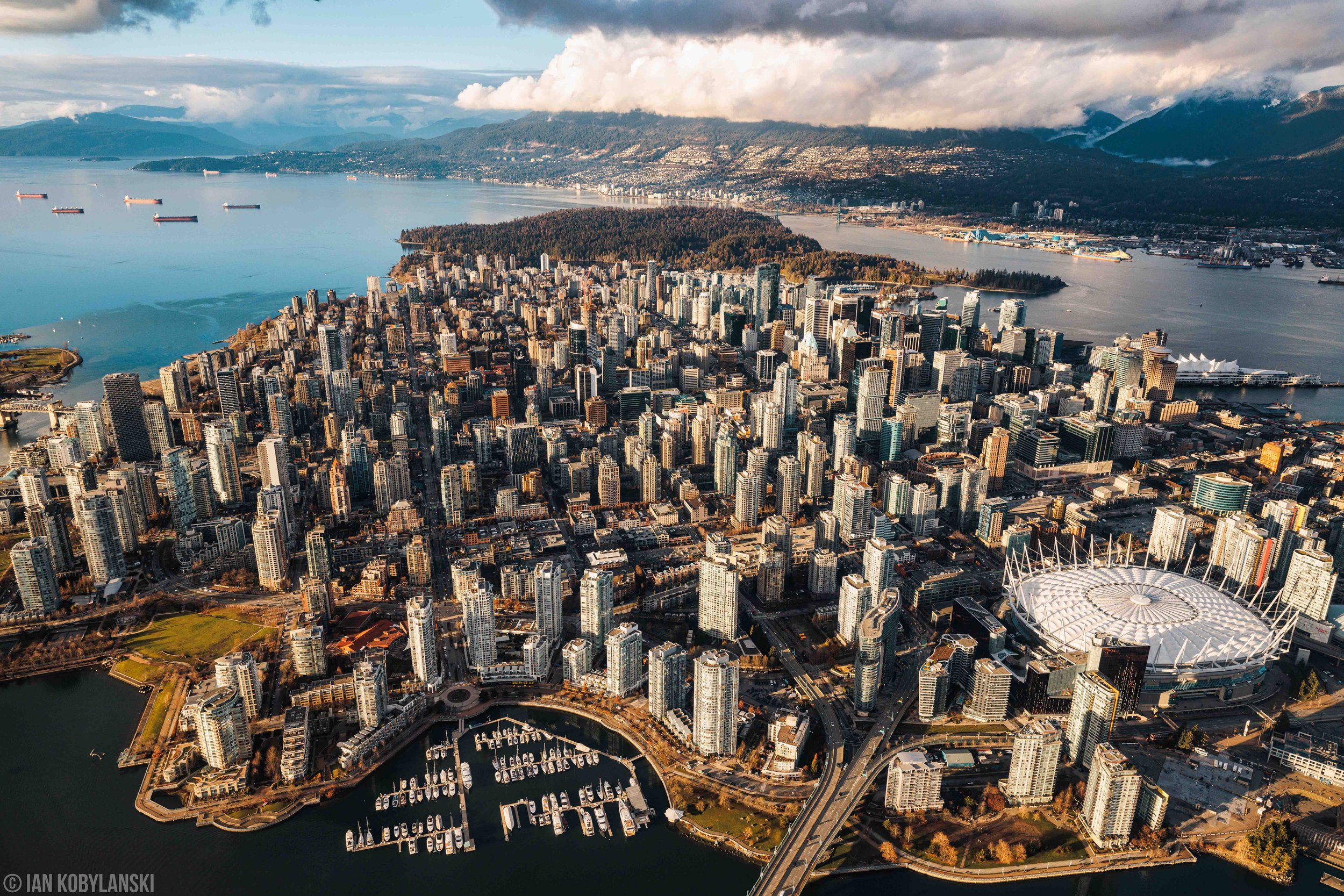  “ Downtown Vancouver Skyline” . Vancouver’s 2023 skyline with a warm sunset glow. Rolling clouds cover the North Shore mountains and let in a soft sun coverage over the water and each building’s facade.  Available as a fine art print here.  