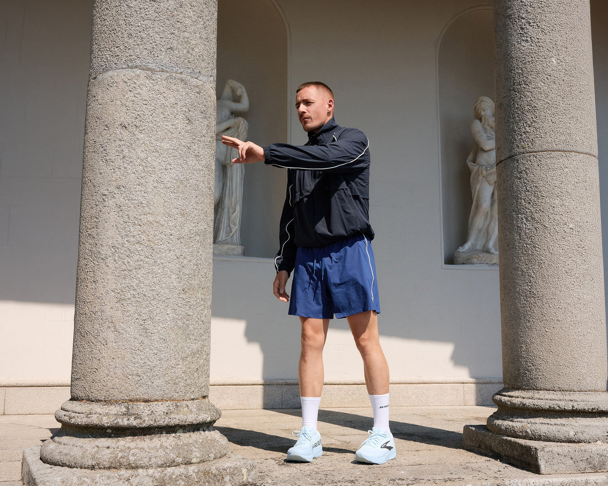 Dermot Kennedy pointing between weathered stone columns and classical statues at Russborough House near Dublin