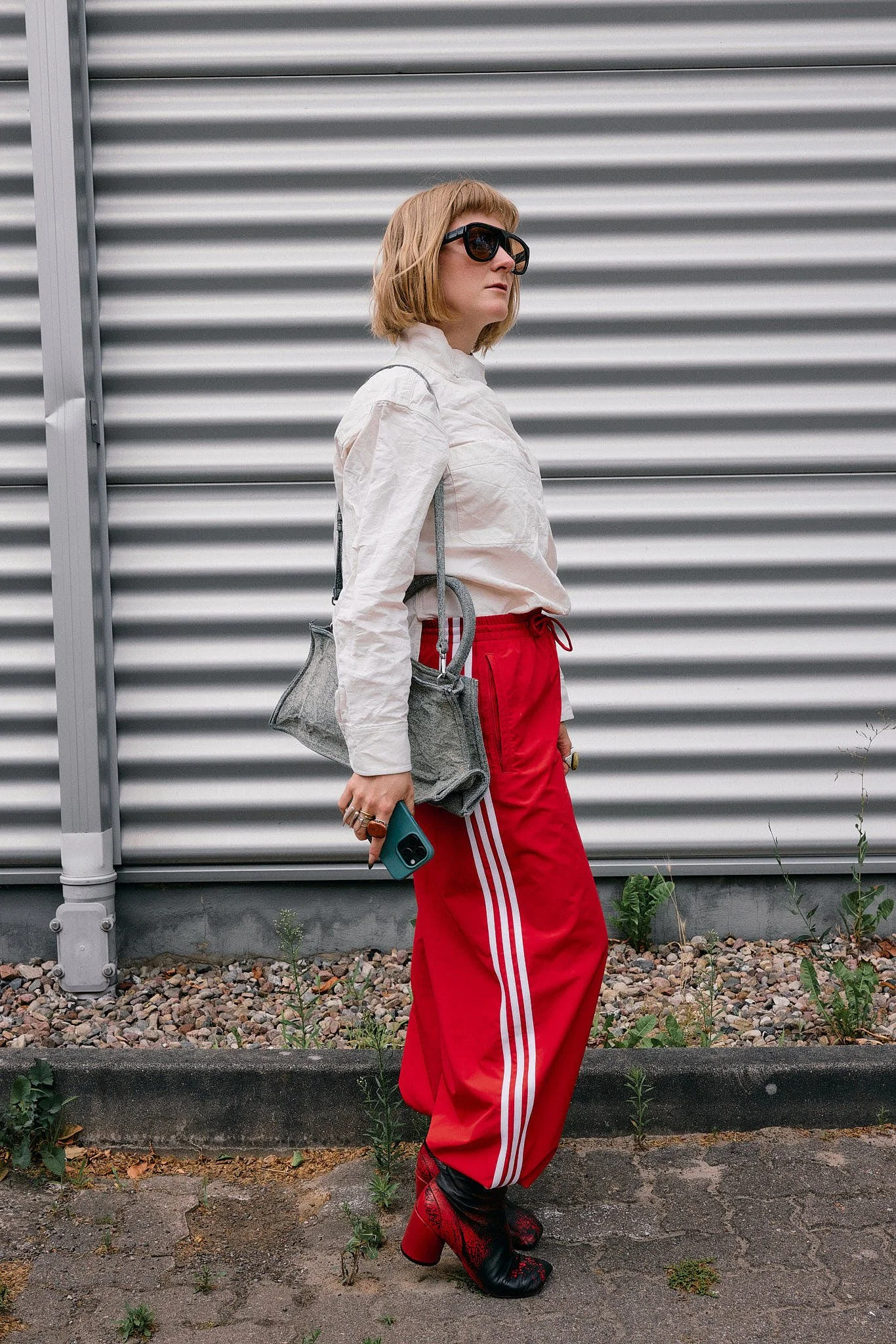 Cream crinkled high-neck jacket with red adidas three-stripe track trousers, a grey felt mini tote and red-and-black snake-print heeled boots, retro sportswear with animal print, Berlin Fashion Week SS27 