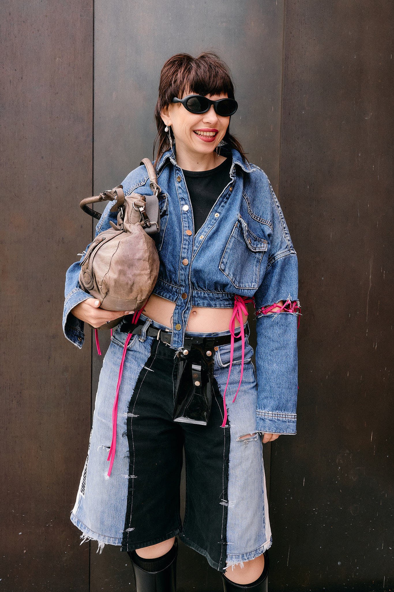  DIY jorts styled with a cropped denim jacket slashed at the sleeves and threaded with pink ribbon, patchwork raw-hem denim shorts and a slouchy leather bag, Berlin Fashion Week SS27 