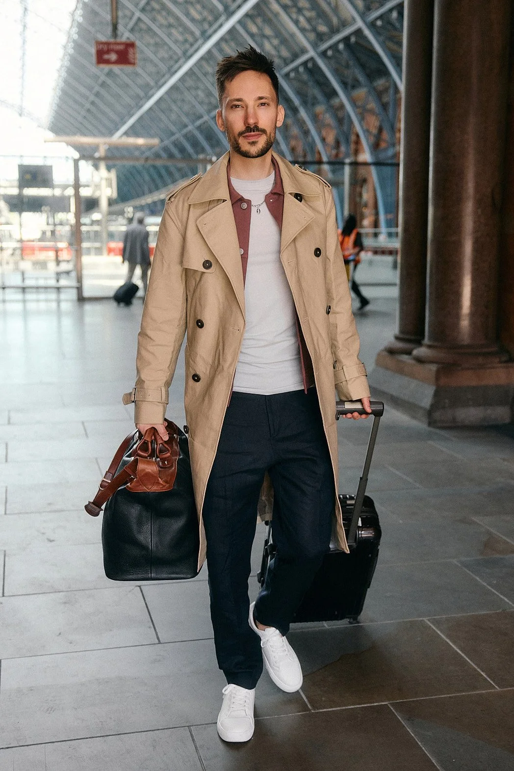 Dating photography portrait in London of man walking with suitcase in hand with confident expression looking at camera leaving train station