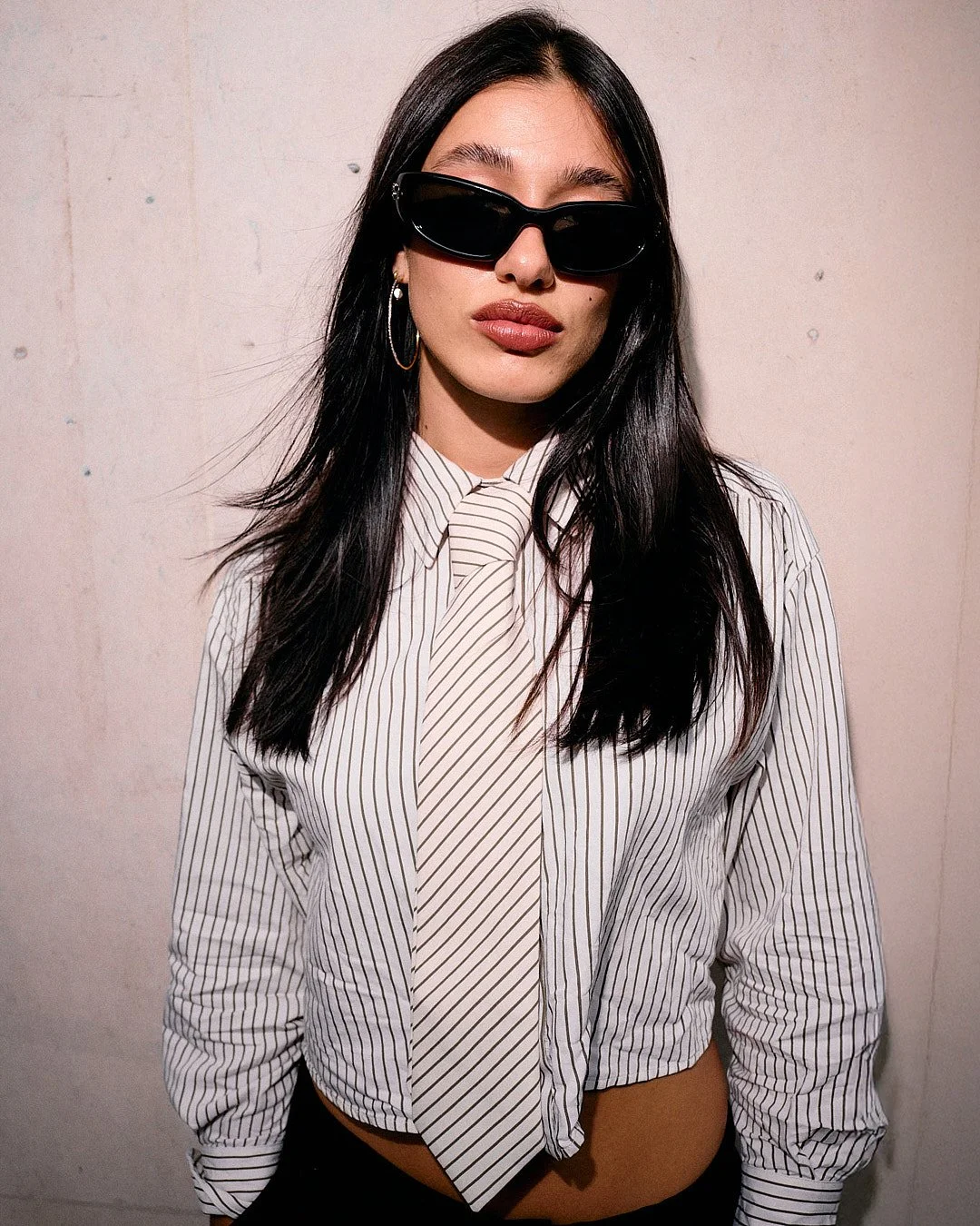 Street fashion portrait at London Fashion Week of music artist flash photo sunglasses striped tie and shirt red lips on cement wall background