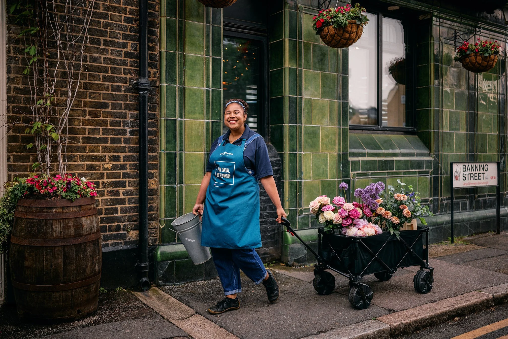 Advertising photography and street photography in London for IBM billboard OOH ad campaign for Wimbledon tennis tournament with lifestyle street photography of florist pulling wagon full of flowers outside green tile pub smiling