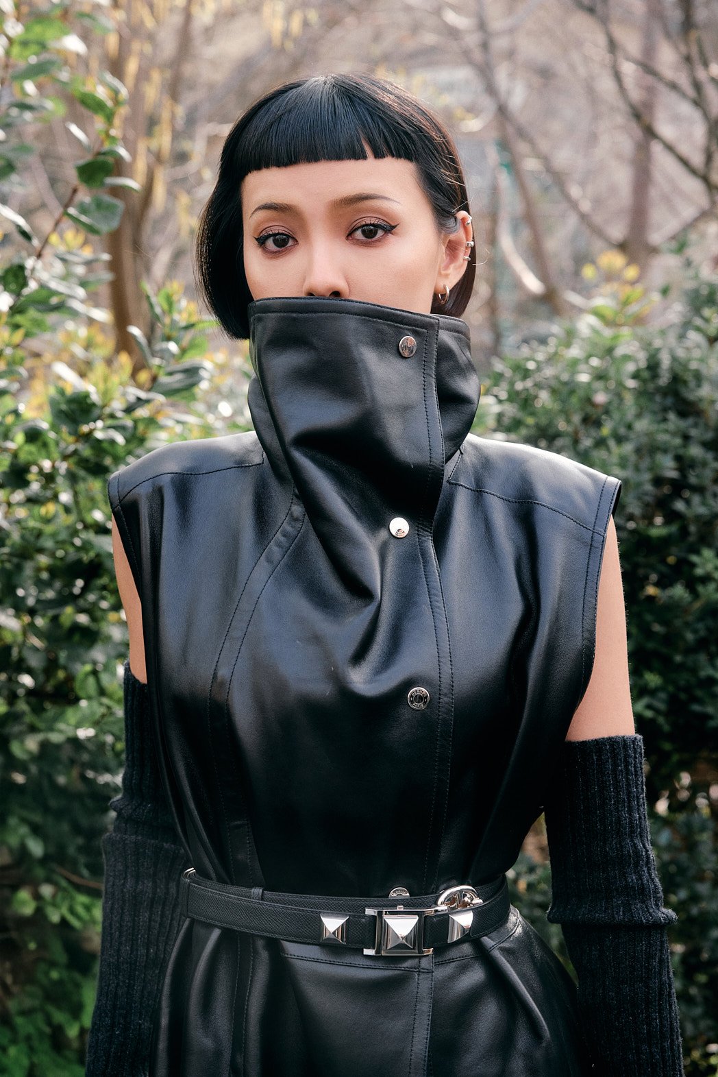 Street style fashion photography at Paris Fashion Week womenswear FW26 by London street photographer of woman with black leather high neck jacket and black bob haircut looking at camera