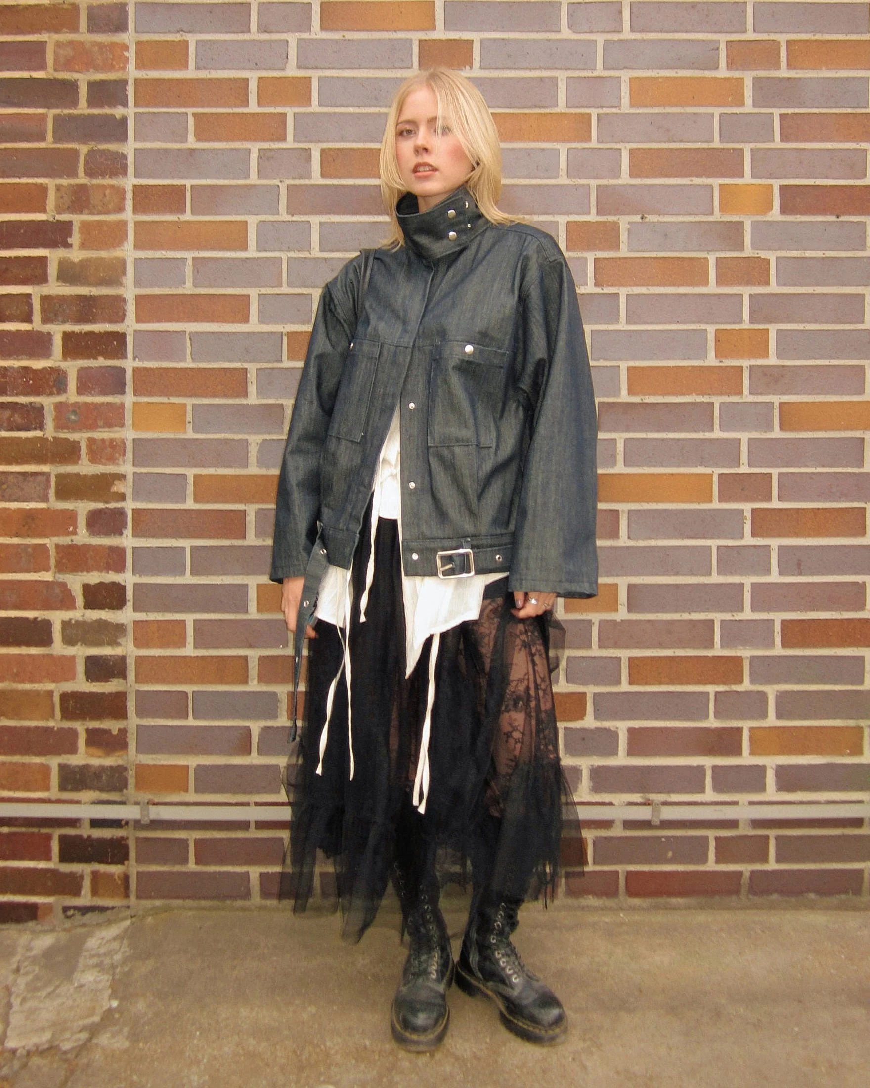 Dark balletcore styling: raw denim jacket with a studded funnel collar buckled at the waist over a black tulle and lace maxi skirt with scuffed lace-up boots, Berlin Fashion Week SS27