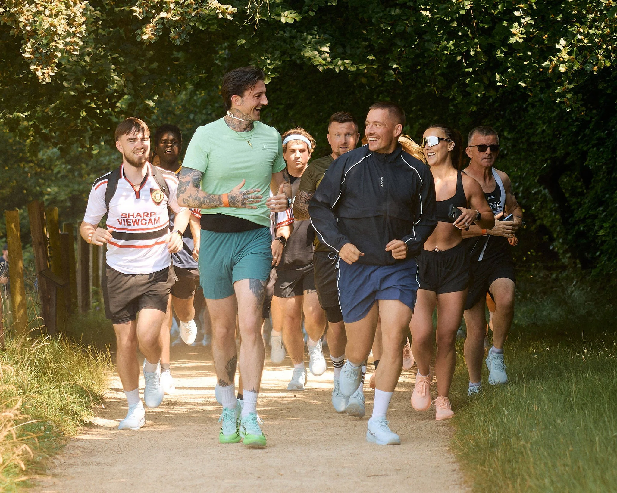 Dermot Kennedy laughing with fans as they run a tree-lined trail during the DK5K, Brooks Running campaign in Ireland