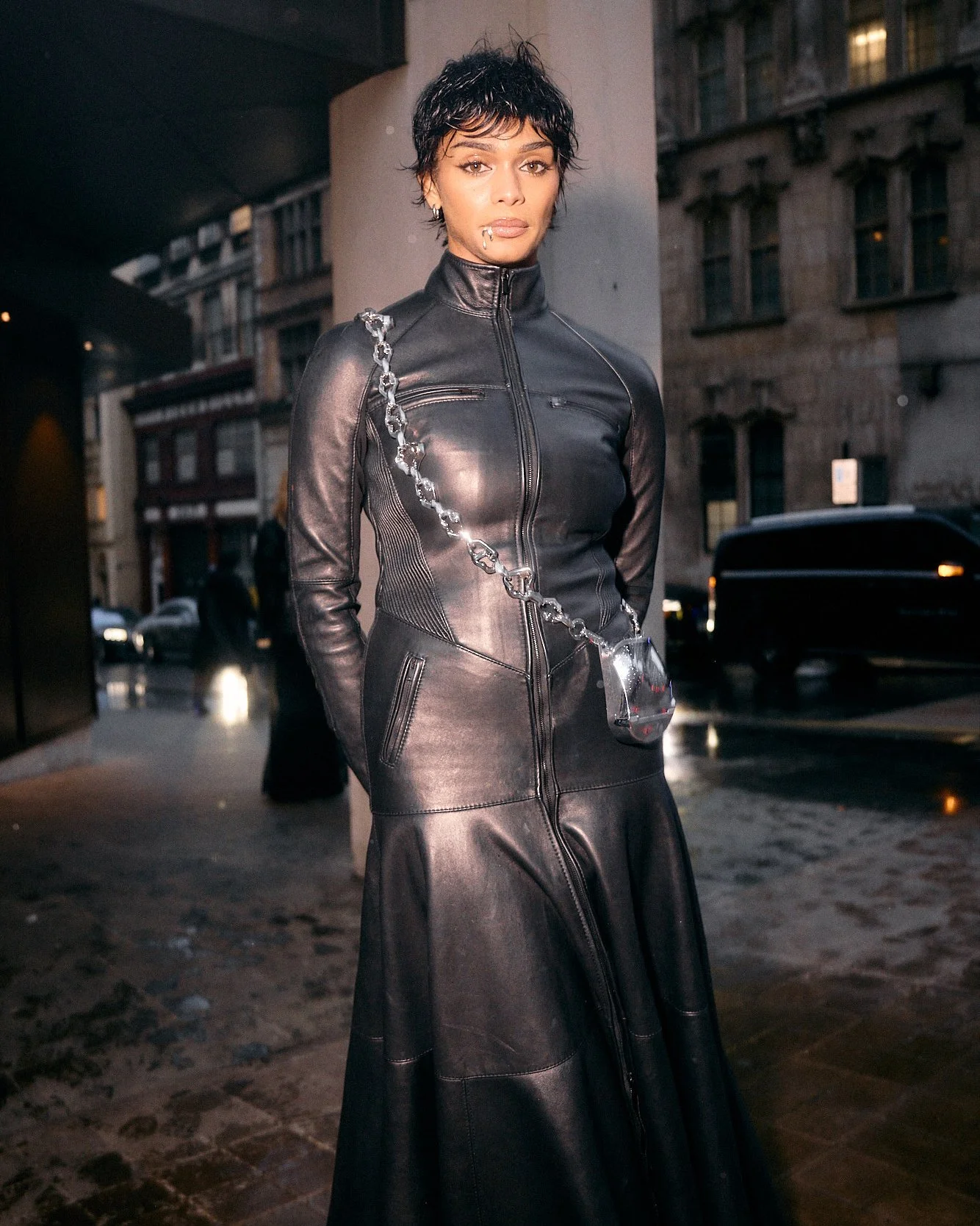 Street fashion photography in London of woman with black leather bodysuit looking at camera flash portrait