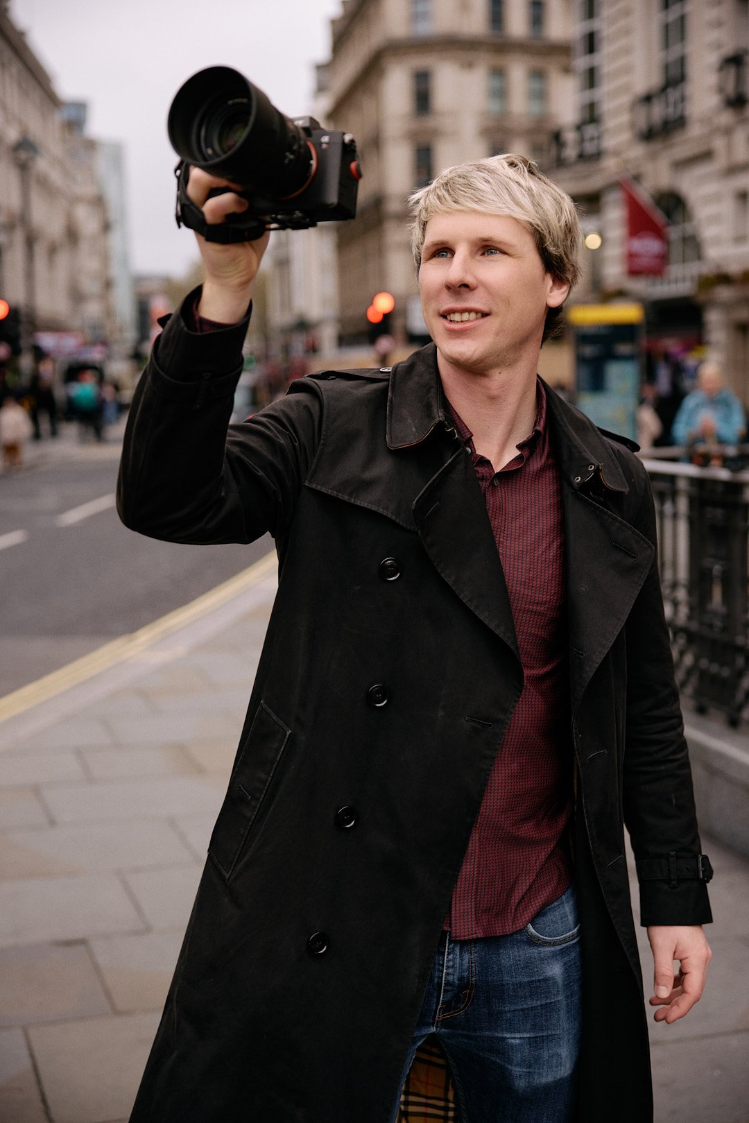 Dating photography portrait of man holding a camera in Piccadilly circus, framing a photo